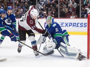 Vancouver Canucks goalie Thatcher Demko stops Colorado Avalanche's J.T. Compher as Vancouver's Chris Tanev, left, defends during the first period of an NHL hockey game in Vancouver, on Friday, March 6, 2020.