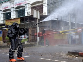 A police officer wearing a protective suit sprays disinfectant on a road amid the spread of coronavirus (COVID-19) in Makassar, South Sulawesi province, Indonesia, March 16, 2020 ..  Antara Foto/Abriawan Abhe/ via REUTERS