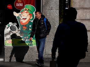 A man is seen on St. Patrick's Day by a cartoon of a Leprechaun as public events were cancelled due to the number of coronavirus cases grow around the world, in Dublin, Ireland, March 17, 2020. (REUTERS/Jason Cairnduff)