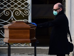 A man touches the coffin of his mother during a funeral service in the closed cemetery of Seriate, Lombardy, on March 20, 2020. (PIERO CRUCIATTI/AFP via Getty Images)