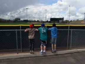 Young fans look over the fences of practice fields at Tempe Diablo Stadium following the cancellation of spring training games due to concerns over the Covid-19 coronavirus, in Tempe, Ariz., March 13, 2020.