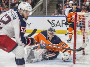 Goaltender Mikko Koskinen of the Edmonton Oilers watches a loose puck go into the corner with Emil Bemstrom of the Columbus Blue Jackets lingering beside the net at Rogers Place on Saturday, March 7, 2020.