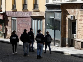 French police, patrolling in a street, look at mock stores in the Montmartre district in Paris as a lockdown is imposed to slow the rate of the coronavirus disease spread in France, March 25, 2020. (REUTERS/Charles Platiau)