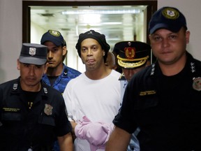 Ronaldinho Gaucho handcuffed and escorted by police at the Supreme Court of Paraguay on March 7, 2020.