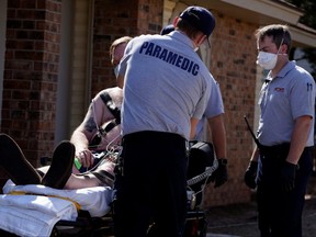 EMS paramedics wearing protective masks and gloves prepare a potential COVID-19 patient for transport in Shawnee, Okla., on Thursday, March 26, 2020.