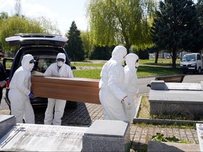 Municipal workers wearing protective gear carry the coffin of a victim of the coronavirus at El Salvador cemetery in Vitoria, Spain, March 27, 2020. (REUTERS/Vincent West)