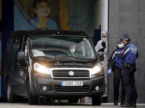 A mortuary car, allegedly carrying the corpse of a person who died of coronavirus, arrives at an ice rink, which will be used as a morgue, in Madrid March 24, 2020. (REUTERS/Juan Medina)