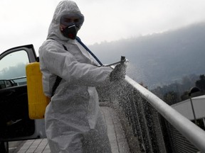 A member of Spain's Military Emergency Unit sprays disinfectant to prevent the spread of the coronavirus COVID-19 at Cabuenes Hospital during a 15-day state of emergency in Gijon, Spain, Wednesday, March 18, 2020.