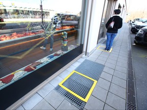 A customer stands in a marked square, denoting a 2 meter seperation, as a preventive measure against the coronavirus disease (COVID-19) outside a butcher in Lausanne, Switzerland, March 19, 2020. (REUTERS/Denis Balibouse)