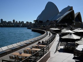 Tables at an open restaurant are seen mostly deserted on a quiet morning at the waterfront of the Sydney Opera House, where scheduled public performances have been cancelled due to COVID-19 coronavirus, in Sydney, Australia, Wednesday, March 18, 2020.