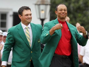Patrick Reed helps Tiger Woods put on the green jacket at the 2019 Masters.