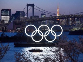 A boat sails past the Tokyo 2020 Olympic Rings in Tokyo, Japan, on Wednesday, March 25, 2020.