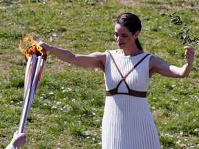 Greek actress Xanthi Georgiou, playing the role of High Priestess, passes the flame to the first torchbearer during the opening of the Olympic flame torch relay for the Tokyo 2020 Summer Olympics on March 12, 2020 in ancient Olympia. (Milos Bicanski/Getty Images)