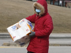 A woman wearing a mask and carrying toilet paper leaves the Pickering Town Centre on Wednesday March 18, 2020. Veronica Henri/Toronto Sun