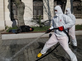 A man enjoys a sunny day as workers in protective suits disinfect Sultanahmet square in response to the spreading coronavirus in Istanbul,Turkey March 21, 2020. (REUTERS/Kemal Aslan)