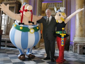 In this March 25, 2015, file photo, French cartoon artist Albert Uderzo poses with people dressed as Asterix (R) and Obelix during a press conference at the Monnaie de Paris where a new series of twelve coins illustrated with Asterix designs entitled "Asterix and the values of the Republic" was presented in Paris.