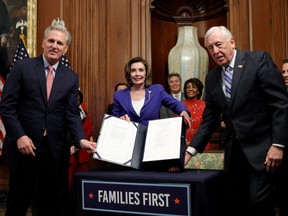 U.S. House Speaker Nancy Pelosi is flanked by House Minority Leader Kevin McCarthy and Majority Leader Steny Hoyer as she displays the $2.2 trillion coronavirus aid bill during a signing ceremony in Washington March 27, 2020. (REUTERS/Tom Brenner)