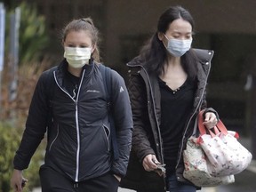 Two women wearing masks walk away from the Life Care Center in Kirkland, Wash., near Seattle, Monday, March 2, 2020.