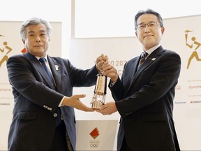 Makoto Noji, head of bureau of culture and sports for Fukushima government, holds the Olympic Flame in lantern with Tokyo 2020 COO Yukihiko Nunomura during an official "handover ceremony" at the J-Village National Training Center, in Naraha Town, Fukushima Prefecture, Japan April 1, 2020, in this photo taken by Kyodo. (Kyodo/via REUTERS)