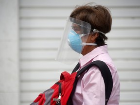 A man wearing a face mask and a face shield waits for a bus before repatriation flights bound for Canada organized by the Canadian embassy for citizens stranded in Peru, as the spread of the coronavirus disease (COVID-19) continues, in Lima, Peru April 4, 2020. (REUTERS/Sebastian Castaneda)