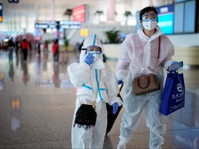 People wearing protective gear are seen at the Wuhan Tianhe International Airport after travel restrictions to leave Wuhan, the capital of Hubei province and China's epicentre of the novel coronavirus disease (COVID-19) outbreak, were lifted, April 8, 2020. REUTERS/Aly Song
