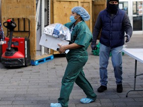 A nurse from Lincoln Hospital wearing scrubs and a protective face mask picks up packages of free food during a food rescue operation run by City Harvest during the outbreak of the coronavirus disease (COVID-19) in the Bronx borough of New York City, New York, April 22, 2020.