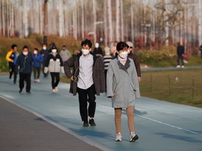 People wearing masks to avoid the spread of the coronavirus disease (COVID-19) walk on a track as they work out at a park in Seoul, South Korea, April 24, 2020.