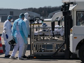 Medical staff help transport a patient infected with the COVID-19 onboard a French air force medicalised Airbus A330 Phenix aircraft on March 31, 2020 at the Bale-Mulhouse airport as part of the Operation Morphee to evacuate COVID-19 patients from the Grand Est region to hospitals in areas where the outbreak has been limited so far. (SEBASTIEN BOZON/AFP via Getty Images)