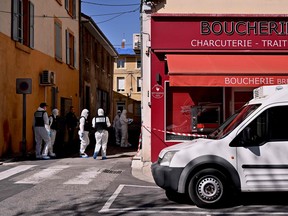 French Police Judiciaire officers wearing protective suits enter in a shop in the centre of Romans-sur-Isere, on April 4, 2020, after a man attacked several people with a knife, killing two and injuring seven before being arrested, according to sources close to the investigation. (JEFF PACHOUD / AFP)