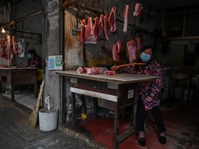 In this photo taken on April 8, 2020, a face-mask clad butcher waits at her stall in Wuhan, China's central Hubei province. (HECTOR RETAMAL/AFP via Getty Images)