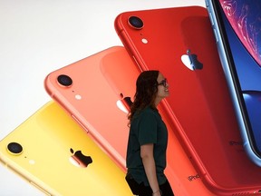 An Apple Store employee walks past an illustration of iPhones at the new Apple Carnegie Library during the grand opening and media preview in Washington, U.S., May 9, 2019.