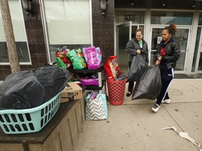 Ashley Reid, who has Renal cell Carcinoma (kidney cancer) and her Austic teenage daughter Jah-Teesha, 15, take all their worldly belongings from the Red Door Shelter on Gerrard St. East to the curb and an awaiting cab. Reid said she was kicked out over a disagreement with staff and is headed to a Canada's Best Value Inn and Suites motel off of Evans Ave. in the west end of the city on Friday April 3, 2020. Jack Boland/Toronto Sun/Postmedia Network