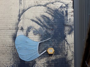 A piece of Banksy street art titled "The Girl with the Pierced Eardrum", now adorned with a protective face mask, is seen at Albion Dock, amid the spread of COVID-19, in Bristol, U.K., April 23, 2020. REUTERS/Rebecca Naden       NO RESALES. NO ARCHIVES. ORG XMIT: GDN