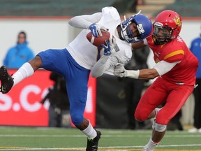 Trivel Pinto from the UBC Thunderbirds (left) makes a catch as he is pressured by Robert Woodson from the U of C Dinos. UBC went on to win the Hardy Trophy in a 34-26 victory over the University of Calgary Dinos in Canada West university football action at McMahon Stadium in NW Calgary, Nov, 14, 2015.