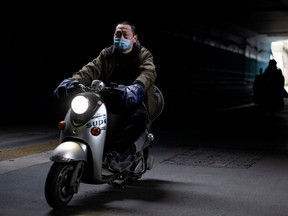 A man wearing a face mask rides a scooter along a street in Wuhan, China's central Hubei province, on Monday, April 6, 2020.