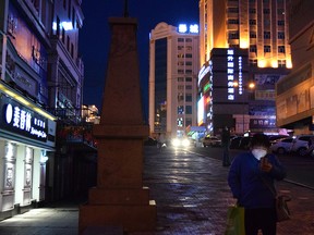 A resident wearing a face mask looks at a smartphone in the city centre in Suifenhe, a city of Heilongjiang province on the border with Russia, as the spread of COVID-19 cases continues in the country, China April 12, 2020.