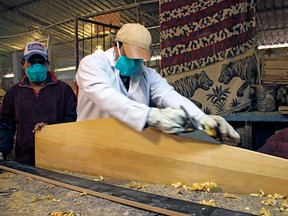 Handout photo released by the Ecuadorean Ministry of Environment of prisoners wearing face masks as they work on the making of coffins in Ambato, Ecuador on April 8, 2020.