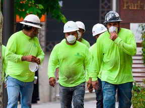 Construction workers wearing face masks head to their lunch break in downtown Los Angeles during morning rush hour on April 30, 2020.
