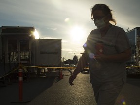 A healthcare worker is silhouetted as they walk past the British Columbia mobile medical unit set up outside of Abbotsford Regional Hospital in Abbotsford, B.C. Tuesday, April 14, 2020.