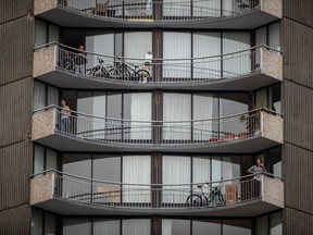People emerge onto apartment balconies after hearing people applauding healthcare workers from other balconies at 7 p.m. in Vancouver's West End, on Sunday, March 22, 2020.