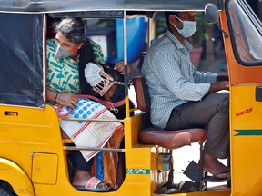 A dog wearing a protective mask is seen with its owner inside an autorickshaw during a 21-day nationwide lockdown to limit the spreading of the COVID-19 coronavirus in Chennai, India, March 30, 2020.