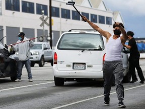 Young men wear face masks while cleaning windshields for extra cash in South Los Angeles amid the coronavirus pandemic on Monday, April 6, 2020.