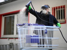 Working student Leon Rottmann coats a shopping trolley with a disinfectant at the mechanic's workshop of the Startup UVIS UV-Innovative Solutions in Cologne, Germany, on April 22, 2020.