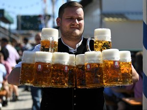 A man holds pints of beer at the opening day of Oktoberfest in Munich, Germany September 21, 2019. (REUTERS/Andreas Gebert)