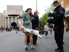 Police officers arrest a demonstrator protesting against restrictions on public life designed to stem the spread of COVID-19, on Rosa Luxemburg Platz in Berlin, Germany, Saturday, April 25, 2020.