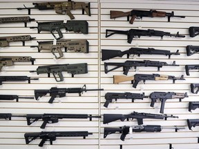 In this Oct. 2, 2018, semi-automatic rifles fill a wall at a gun shop in Lynnwood, Wash. Starting Tuesday, Jan. 1, 2019.