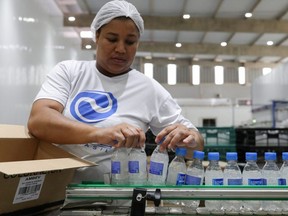 A employee carries ethanol-based hand sanitizers in AGE do Brasil factory in Vinhedo, Brazil, March 25, 2020.