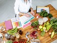 Dietitian writing a diet plan, view from above on the table with different healthy products and drawings on the topic of healthy eating