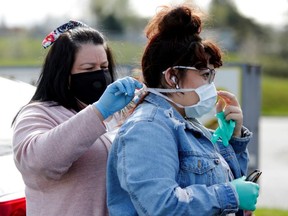 Kahealani Candido, whose boyfriend is at the Monroe Correctional Facility, the site of a recent inmate protest after several inmates and staff tested positive for COVID-19, helps her boyfriend's mom Deborah Del Toro put on a mask before protesting outside the complex as efforts continue to help slow the spread of the coronavirus, in Monroe, Wash., Tuesday, April 14, 2020.