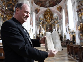 Thomas Groener, pastor from Oberammergau, presents the so called "Book of Death" from the bubonic plague in the 17th century in Oberammergau, Germany, April 9, 2020. (REUTERS/Andreas Gebert)
